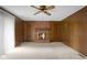 A charming living room has a brick fireplace, neutral carpet, wood paneling, and ceiling fan at 3235 Flintwood Dr, Columbus, IN 47203