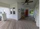Charming front porch featuring a wooden deck, rocking chairs, stone pillars, a ceiling fan, and a red door at 4740 Milton St, Coatesville, IN 46121