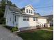 Angled exterior view showcases white siding, windows, and a set of steps leading to the back door and lush green lawn at 4740 Milton St, Coatesville, IN 46121