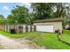 A detached one car garage with a white door and tan siding sits on a grassy lot with a wooden fence at 504 Broadway Ave, Arcadia, IN 46030