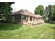 Backyard featuring a brick home with a deck, surrounded by a lush green lawn and manicured landscaping at 5943 Red Maple Dr, Indianapolis, IN 46237