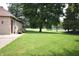 Spacious backyard with a well-kept lawn, mature trees, and a white fence, providing ample space for outdoor activities at 5943 Red Maple Dr, Indianapolis, IN 46237