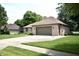 Brick home featuring a two-car garage, surrounded by a green lawn and mature trees, offering a serene setting at 5943 Red Maple Dr, Indianapolis, IN 46237