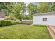 A well-maintained backyard with a green lawn, mature trees, and a glimpse of a detached garage and neighboring houses at 6045 Crittenden Ave, Indianapolis, IN 46220