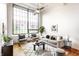 Bright living room featuring hardwood floors, a large window, a ceiling fan and modern furnishings at 624 E Walnut St # 48, Indianapolis, IN 46204