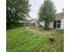 A grassy backyard with a patio and partial metal pergola extending from a white house with a sliding glass door at 7307 Barnwell Pl, Indianapolis, IN 46217