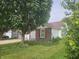 A cozy home featuring brick accents, a well-manicured lawn, and mature trees offering shade and privacy at 7307 Barnwell Pl, Indianapolis, IN 46217