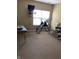 Bright carpeted exercise room featuring fitness equipment, a window, and a wall-mounted television at 7357 Lake Lakota Dr, Indianapolis, IN 46217