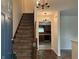 Welcoming foyer featuring a staircase with carpet, chandelier lighting, and views into the kitchen at 7667 Madden Ln, Fishers, IN 46038