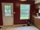 Kitchen with white door leading to the fenced yard, red walls and wood cabinets at 7667 Madden Ln, Fishers, IN 46038