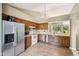 Open kitchen with wood cabinets, stainless steel refrigerator, laminate floor, and view to the dining area at 7831 Bayridge Dr, Indianapolis, IN 46236