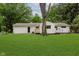 View of the backyard with lush grass, a white home with a small porch and many trees at 8115 Englewood Rd, Indianapolis, IN 46240