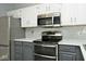 Kitchen close-up with stainless steel appliances, gray and white cabinets, and tile backsplash at 8247 Cape N Dr, Indianapolis, IN 46256