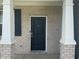 Close-up of the front door featuring brick accents and white columns on a covered porch at 8969 Faulkner Dr, Indianapolis, IN 46239