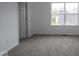 Bedroom with neutral carpeting, white walls and trim, and a bright window that overlooks the street at 9516 Bauhaus Way, Indianapolis, IN 46240