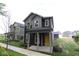 Attractive two-story house featuring a covered porch, gray siding, a yellow door, and fresh landscaping at 9516 Bauhaus Way, Indianapolis, IN 46240