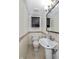 Cozy half bathroom featuring pedestal sink and tiled walls at 10016 Penrith Dr, Indianapolis, IN 46229