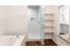 Bright bathroom with marble shower, soaking tub, and an adjacent walk-in closet with built-in shelves at 1210 Churchman Ave, Indianapolis, IN 46203