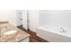 Modern bathroom featuring granite countertops, a tub with marble surround, and stylish wood-look flooring at 1210 Churchman Ave, Indianapolis, IN 46203