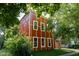 Charming two-story home with red exterior and white trim, framed by mature trees, offering a welcoming curb appeal at 1210 Churchman Ave, Indianapolis, IN 46203