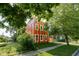 Stylish two-story home with a unique red exterior and white trim, surrounded by lush greenery and a well-manicured lawn at 1210 Churchman Ave, Indianapolis, IN 46203