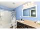Well-lit bathroom with a shower and tub, blue walls, and a vanity with a countertop basin at 1314 Old Heritage Pl, Greenwood, IN 46143