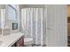 Bathroom with cherry vanity, shower with white floral curtain, and a window at 13327 Hockley Dr, Fishers, IN 46037