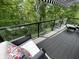 Relax on the deck with glass railings, surrounded by lush trees and a comfortable seating area at 14442 Treasure Creek Ln, Fishers, IN 46038
