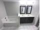 Bright bathroom featuring double vanity with dark cabinets and a bathtub with tiled surround at 1556 N Euclid Ave, Indianapolis, IN 46201