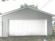View of the detached two car garage with white door and light gray siding at 1556 N Euclid Ave, Indianapolis, IN 46201