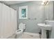 Well-lit bathroom featuring a pedestal sink, toilet, shower, and a window allowing ample natural light at 17138 Joliet Rd, Westfield, IN 46074