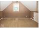 Finished attic space with neutral carpeting, a window for natural light, and sloped ceilings at 2325 N Talbott St, Indianapolis, IN 46205