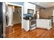Well-equipped kitchen with stainless steel appliances, white cabinets, hardwood floors, and adjacent staircase at 2325 N Talbott St, Indianapolis, IN 46205