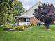 Landscaped backyard featuring a porch, swing, manicured lawn, and beautiful flower beds at 2925 Morgan Trl, Martinsville, IN 46151