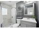Updated bathroom features modern tile in the shower with a grey vanity and a decorative shelf at 3307 N College Ave, Indianapolis, IN 46205