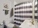 Bathroom with gray and white striped shower curtain, toilet and white sink and vanity at 3329 Main St, Anderson, IN 46013