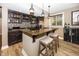 Basement bar featuring granite countertop, dark cabinetry, mosaic tile backsplash and a stainless steel refrigerator at 3429 Woodham Pl, Carmel, IN 46033