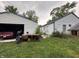 Exterior view of detached garage and house; both situated in overgrown yard at 3440 Brewer Dr, Indianapolis, IN 46222
