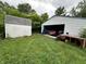 Exterior view of detached garage and shed; both situated in overgrown yard at 3440 Brewer Dr, Indianapolis, IN 46222
