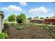 Landscaped backyard with a garden area, mature trees, and a view of the house exterior at 409 Hanley St, Plainfield, IN 46168