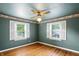 An empty bedroom with hardwood floors, a ceiling fan, and 2 shuttered windows at 409 Hanley St, Plainfield, IN 46168