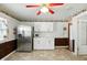 White kitchen featuring stainless steel appliances, bright lighting, brick accent wall, and vintage wallpaper border at 409 Hanley St, Plainfield, IN 46168