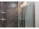 Modern bathroom shower with black marble tile, glass door, and chrome fixtures at 4742 Kingsley Dr, Indianapolis, IN 46205