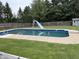 In-ground pool featuring a slide, diving board, and mature trees, all enclosed by a wooden fence at 4760 Winterberry Pl, Columbus, IN 47201