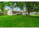 Lush backyard with mature trees and partial view of the single-story home at 50 Crestview Dr, Greenwood, IN 46143