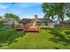View of the home's backyard featuring a wooden deck, green lawn and mature trees at 5010 Donner Ln, Indianapolis, IN 46268