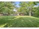 The lush backyard has a sprawling lawn, mature trees, and view of the red brick home at 5841 N Parker Ave, Indianapolis, IN 46220