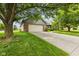 Well-maintained front yard with lush green lawn and mature trees framing a brick home with a two-car garage at 6629 Woodcrest Dr, Avon, IN 46123