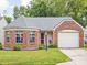Charming brick home featuring a well-manicured lawn, attached garage, and lovely front garden at 6637 Sundown S Dr, Indianapolis, IN 46254