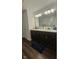 A bathroom with double vanity and wood-look floors and a view of the standing shower in the mirror at 6842 Arrowhead Dr, Brownsburg, IN 46112